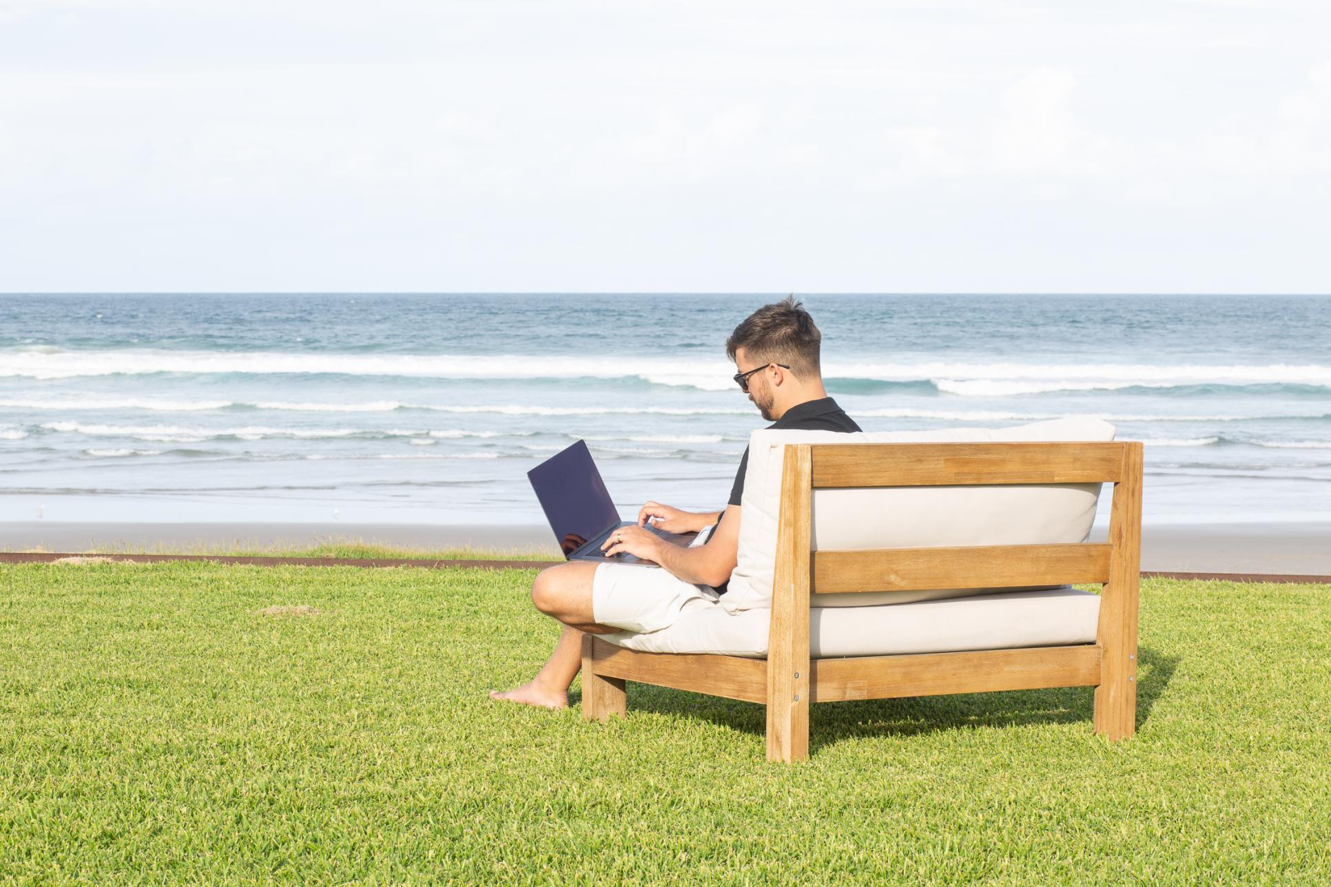 Developer working on a sofa outside with the ocean in the background